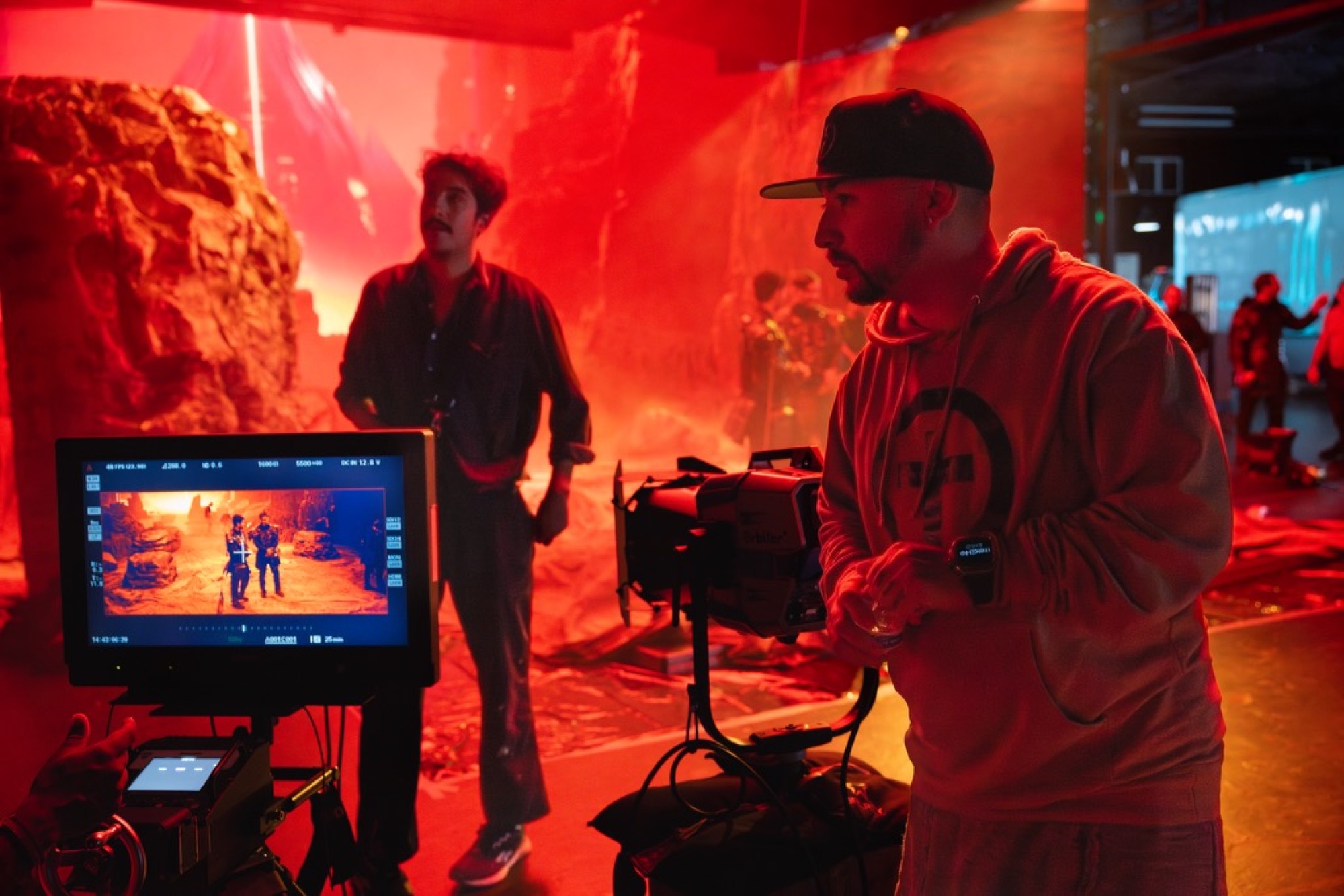Mike Ho directing beside a camera on a vivid red set